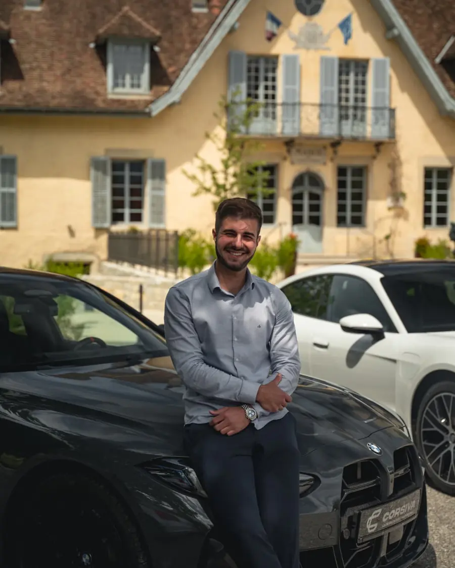 Un conseiller Corsiva devant un château, voitures du parc derrière lui