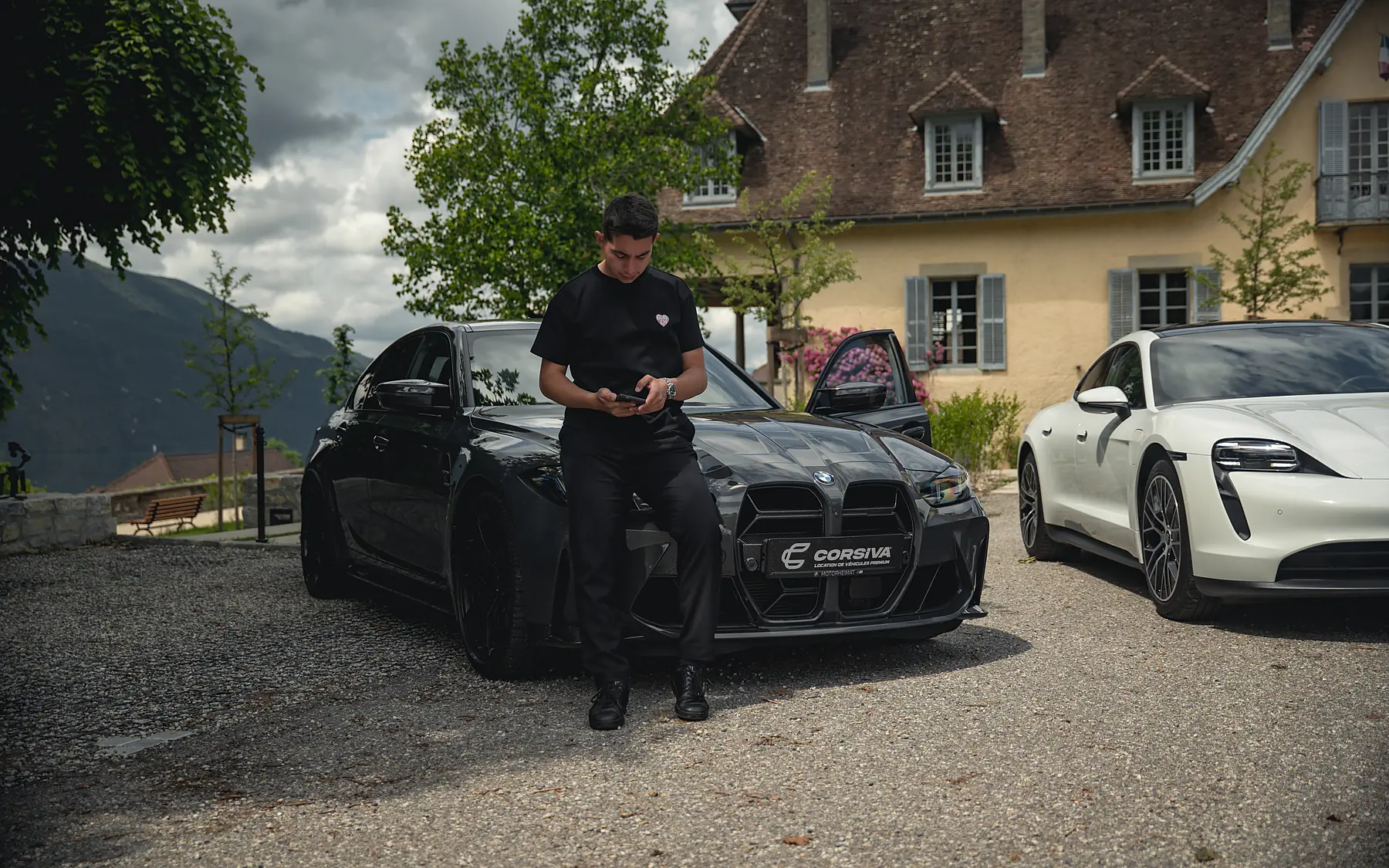 Un membre de l’équipe Corsiva devant la BMW M3 Compétition et la Porsche Taycan