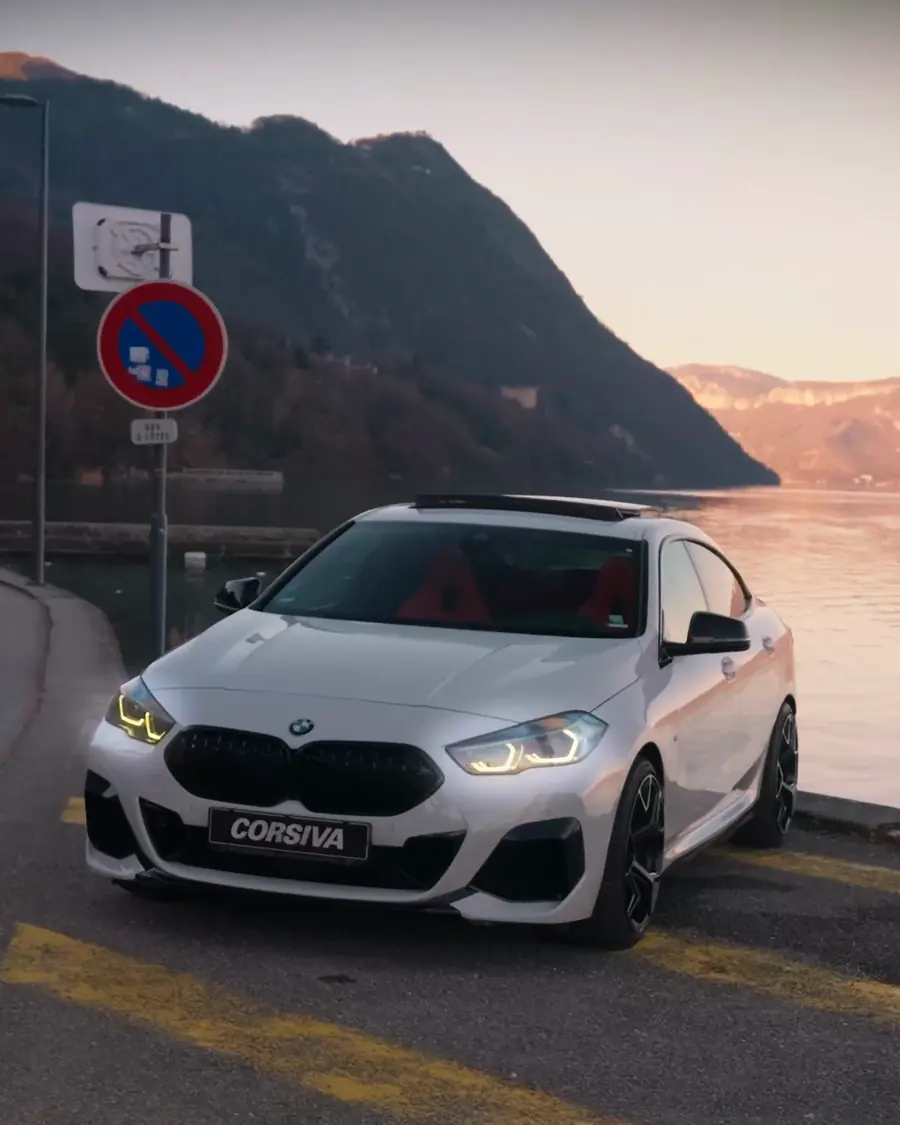 BMW blanche plaquée Corsiva au bord d'un lac, au coucher du soleil