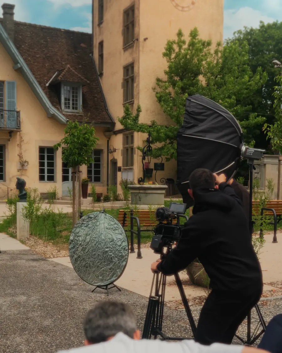 Équipe de tournage devant un château, voiture Corsiva