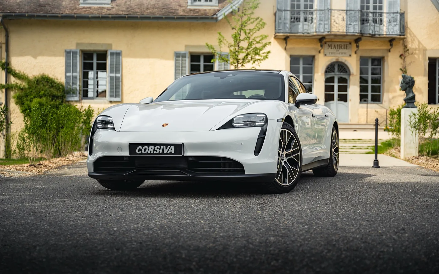Porsche Taycan blanche du parc Corsiva devant un manoir