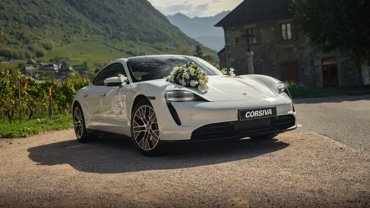 Porsche Taycan blanche fleurie devant les vignes de Savoie