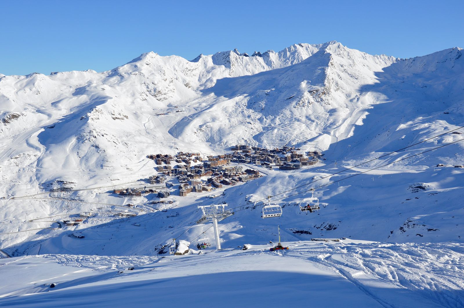 La station de Val Thorens au pied de sommets enneigés, avec un télésiège au premier plan, par un matin ensoleillé