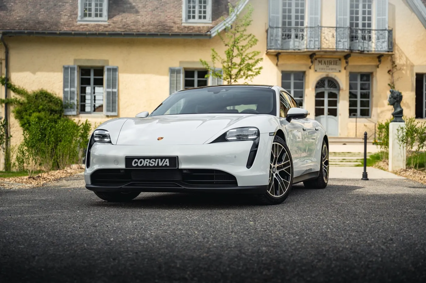 Porsche Taycan blanche Corsiva devant la façade d'un château