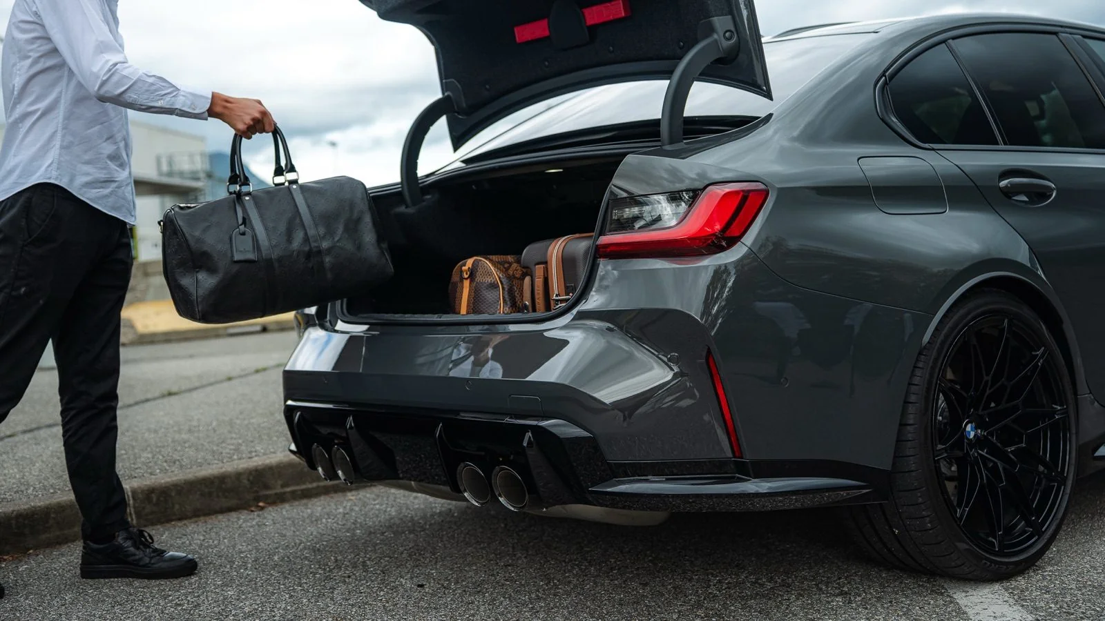 BMW M3 Corsiva, coffre ouvert, bagages chargés au départ