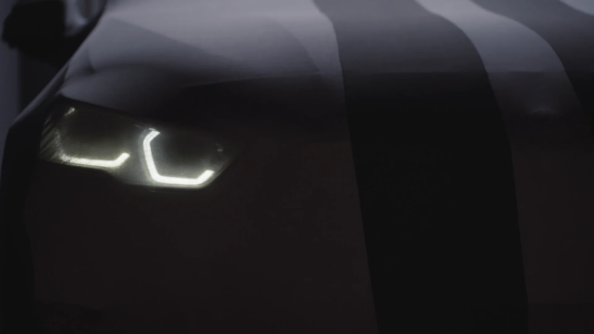 Phares allumés d'une BMW M3 Corsiva dans la nuit